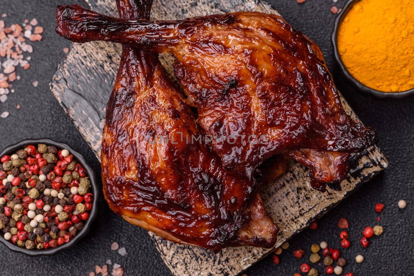 Duck, chicken leg or thigh grilled on a dark concrete background. Duck confit, Asian food with salt and spices