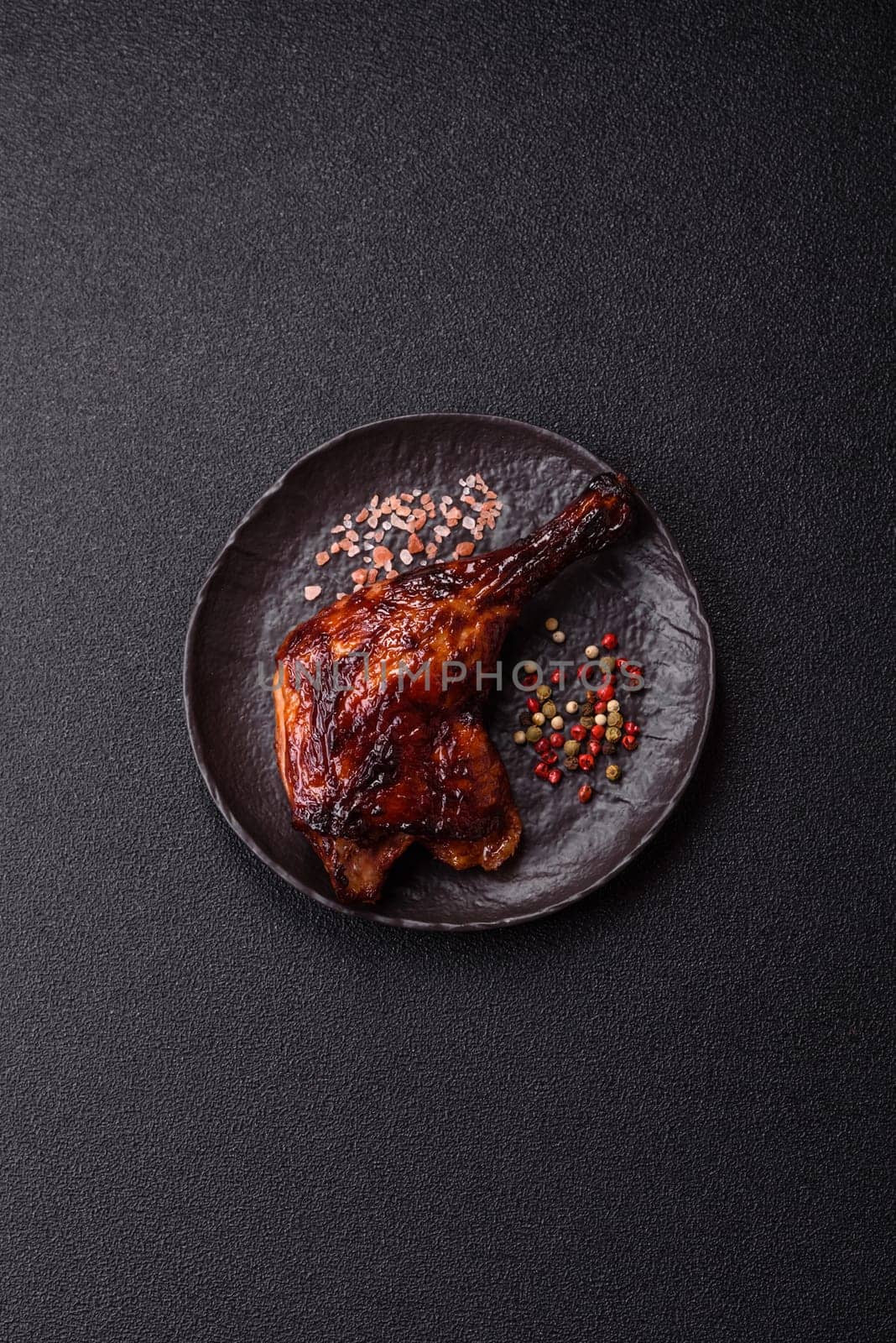 Duck, chicken leg or thigh grilled on a dark concrete background. Duck confit, Asian food with salt and spices