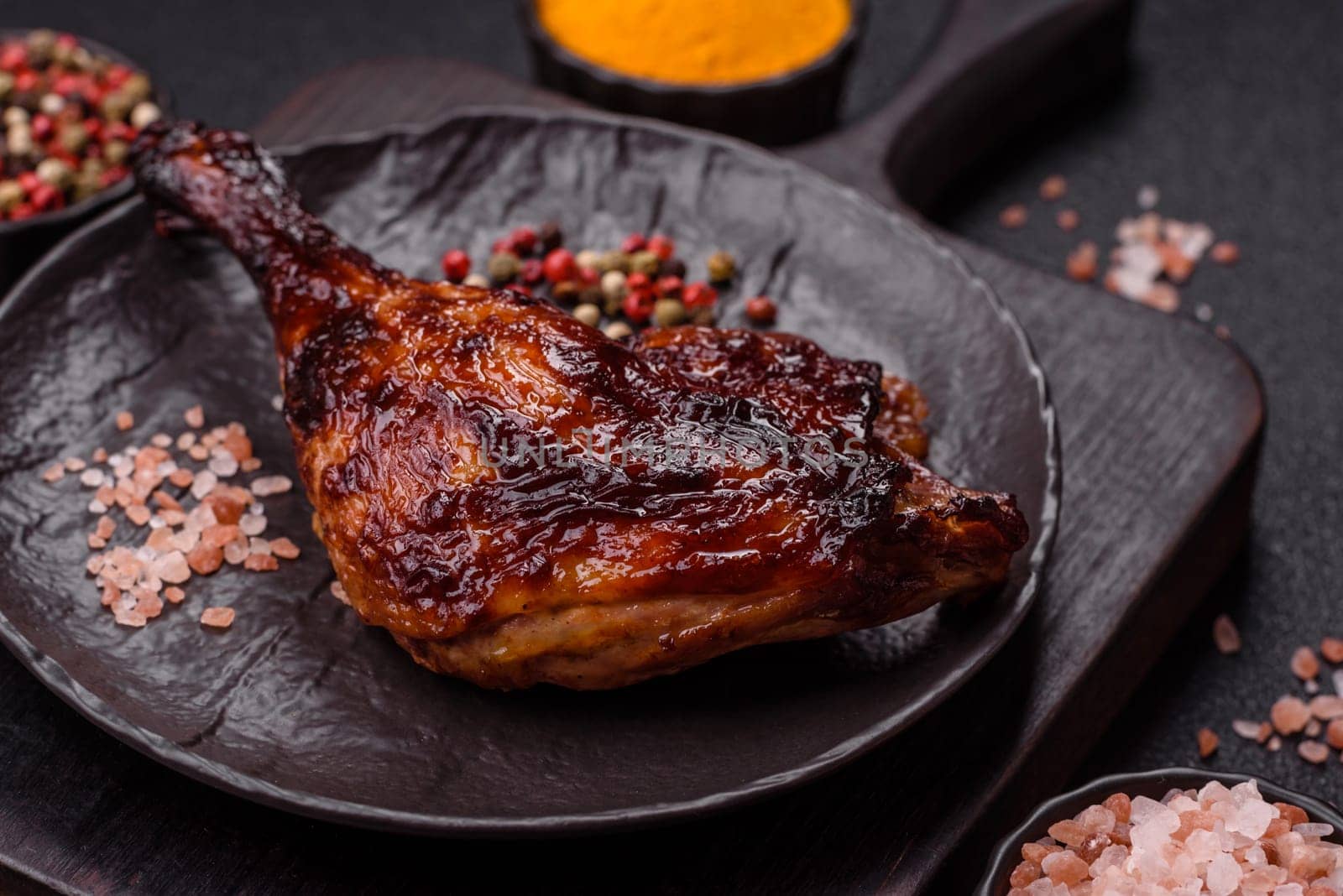 Duck, chicken leg or thigh grilled on a dark concrete background. Duck confit, Asian food with salt and spices