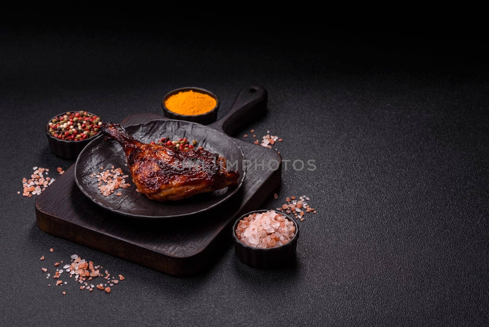 Duck, chicken leg or thigh grilled on a dark concrete background. Duck confit, Asian food with salt and spices