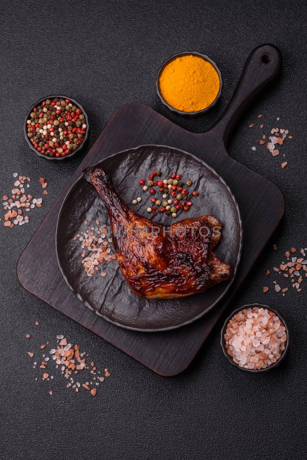 Duck, chicken leg or thigh grilled on a dark concrete background. Duck confit, Asian food with salt and spices