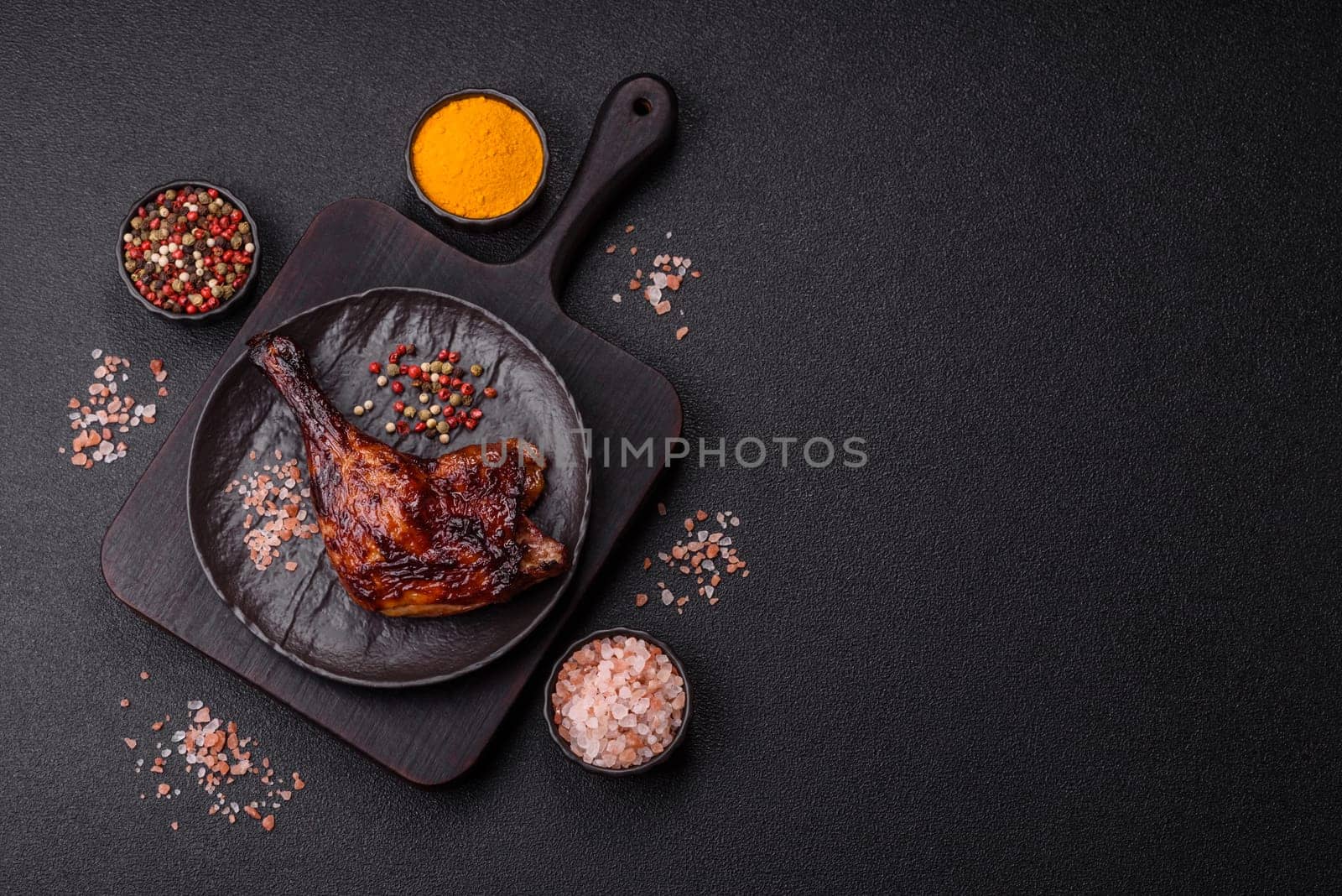 Duck, chicken leg or thigh grilled on a dark concrete background. Duck confit, Asian food with salt and spices