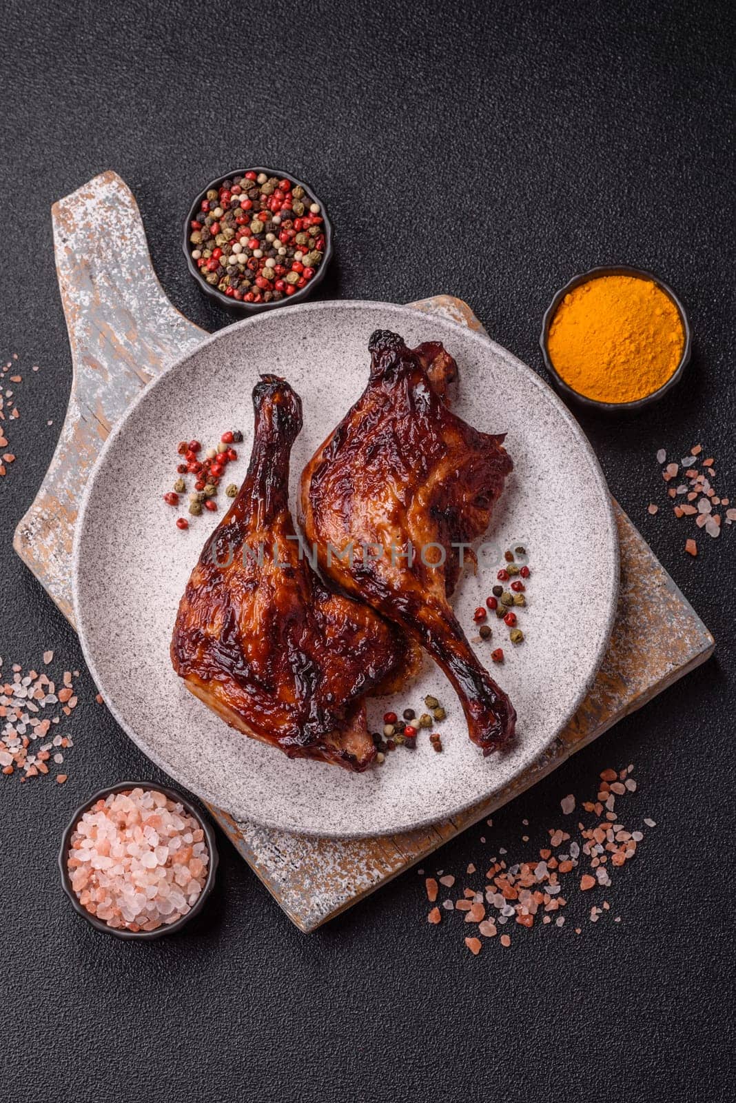 Duck, chicken leg or thigh grilled on a dark concrete background. Duck confit, Asian food with salt and spices