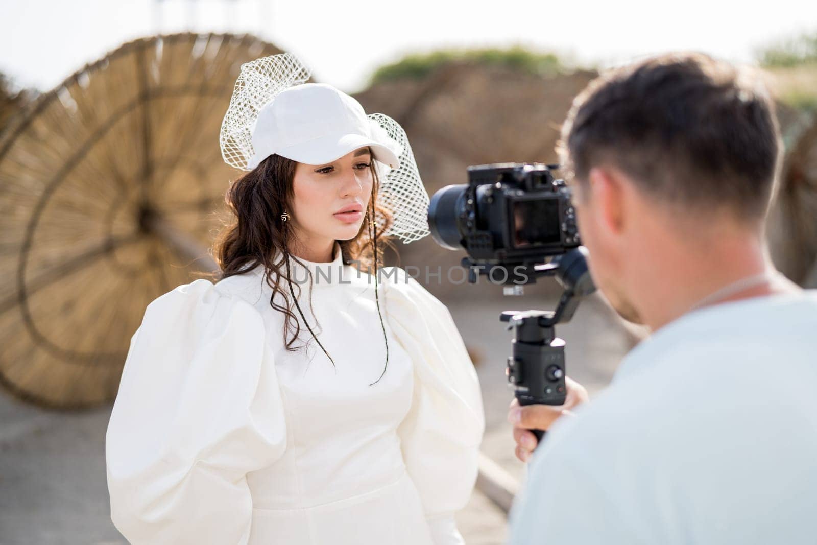 Photographer photographs bride standing on the beach with a digital camera on a tripod. Side view. High quality photo
