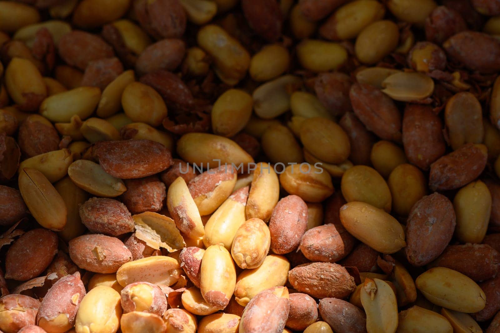 A rich collection of raw peanuts in various colors rests under gentle sunlight, showcasing their natural textures and imperfections. Serenity reigns in this botanical haven.