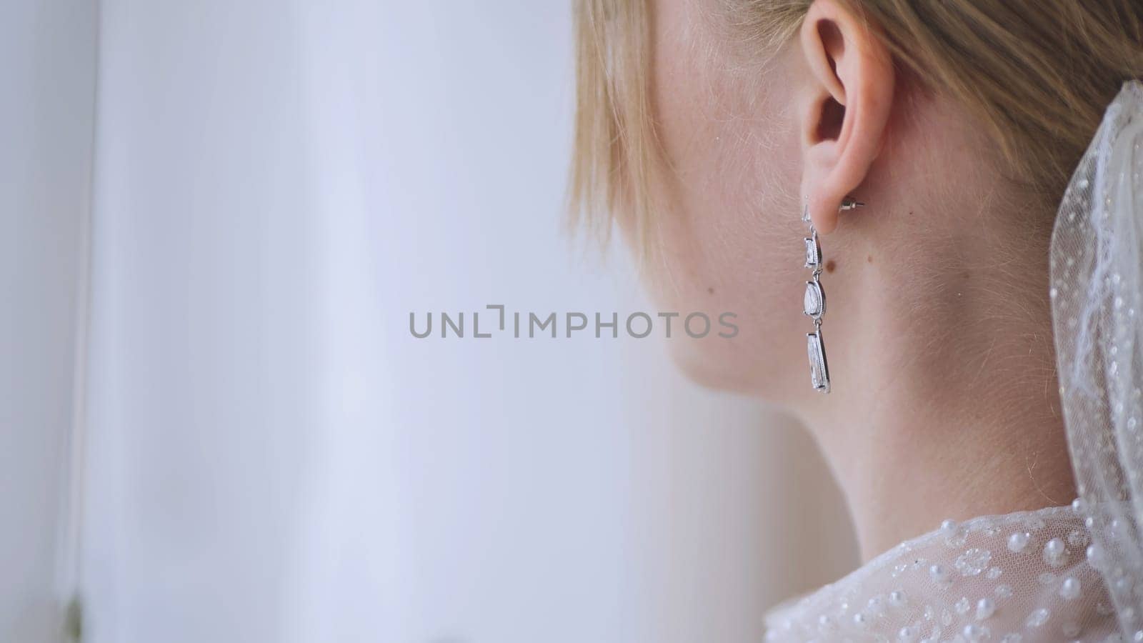 Bride wearing delicate pearl earrings, complementing bridal attire with sophisticated elegance