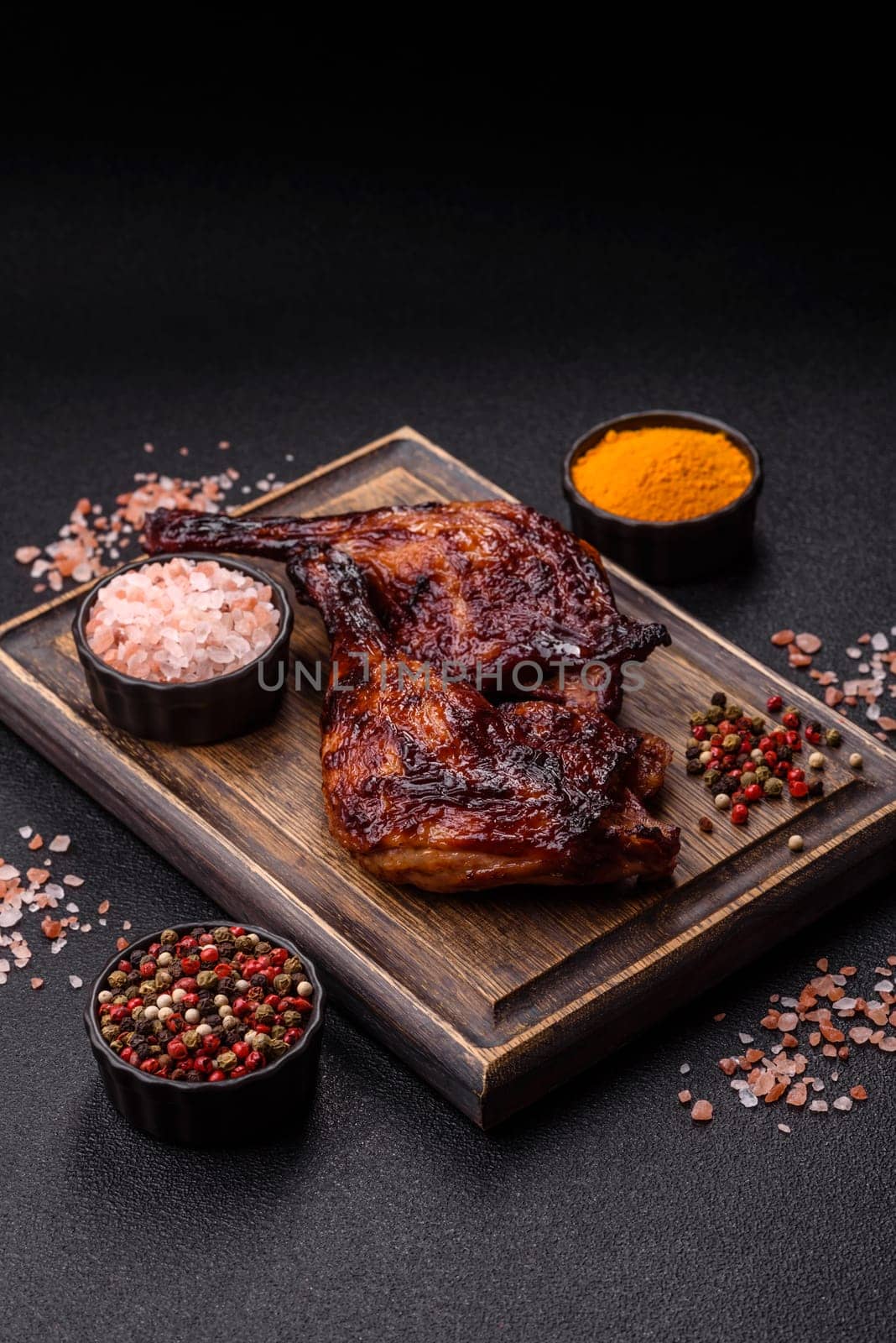 Duck, chicken leg or thigh grilled on a dark concrete background. Duck confit, Asian food with salt and spices