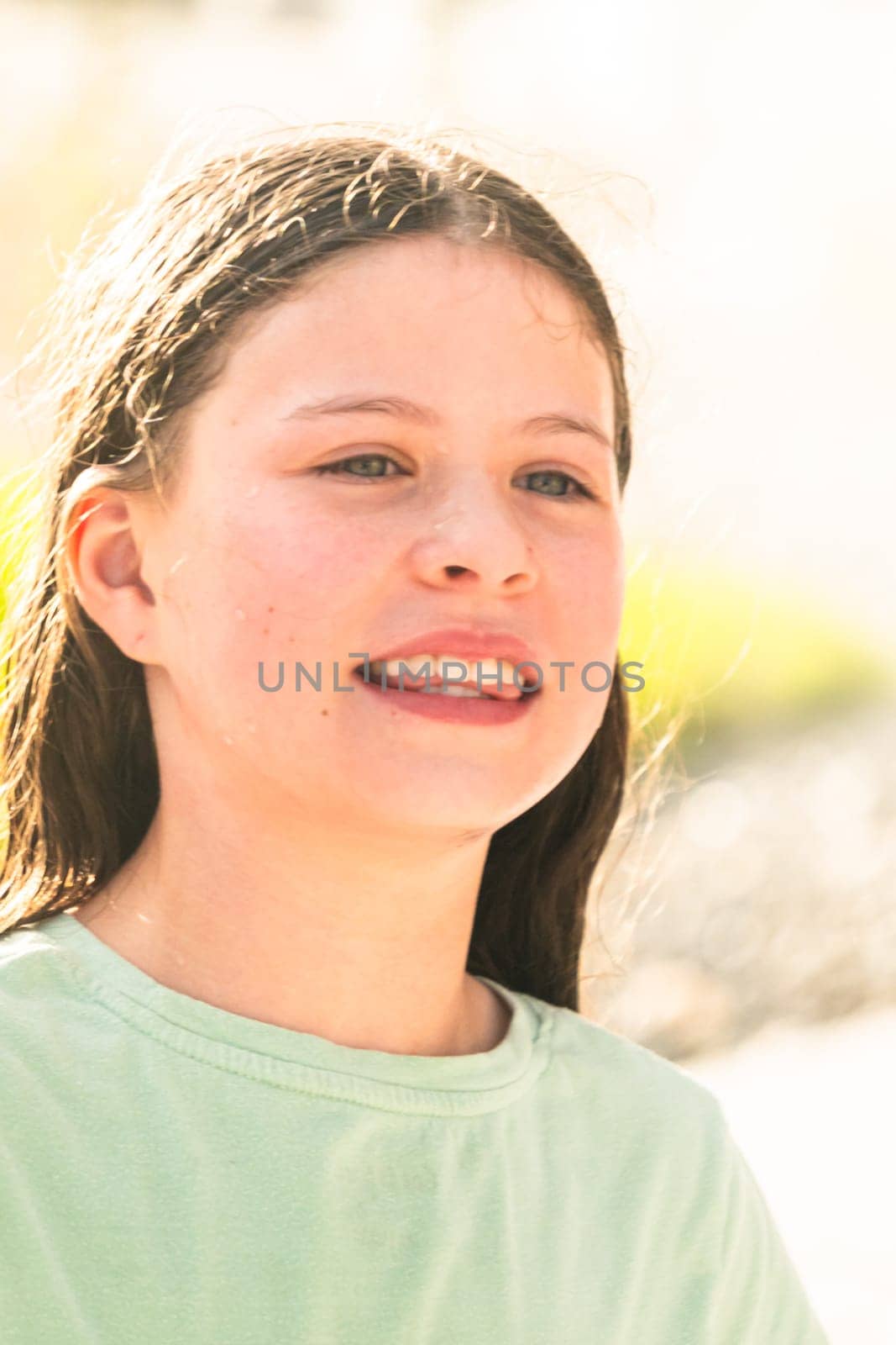A joyful young girl gleefully gets soaked in refreshing water mist during a hot summer day.