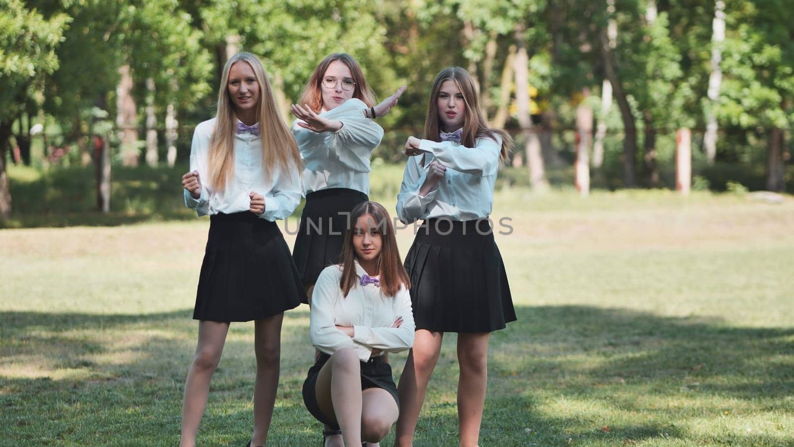 Funny schoolgirls posing and goofing around in a meadow