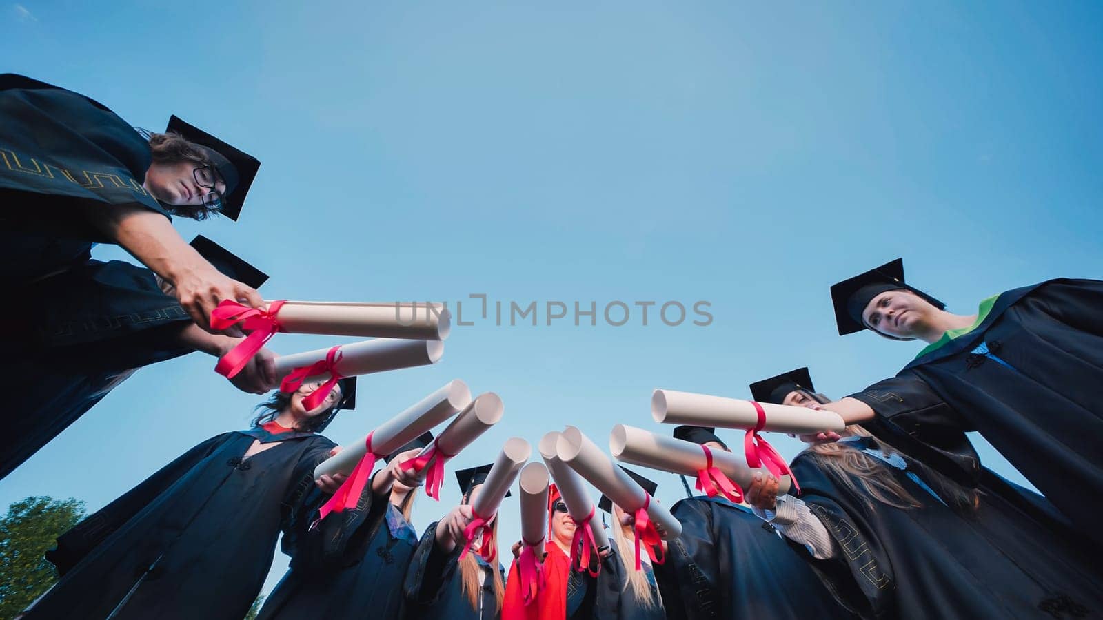 Group of students holding their diplomas forming a circle, celebrating their graduation day