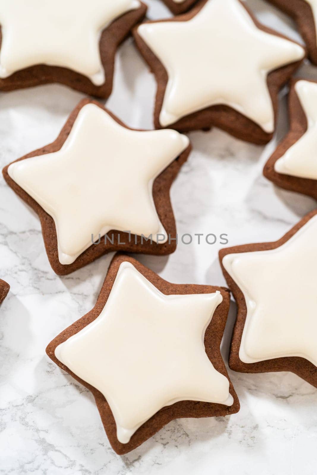 A neat arrangement of gingerbread star cookies covered in white royal icing, emphasizing their festive and uniform design.