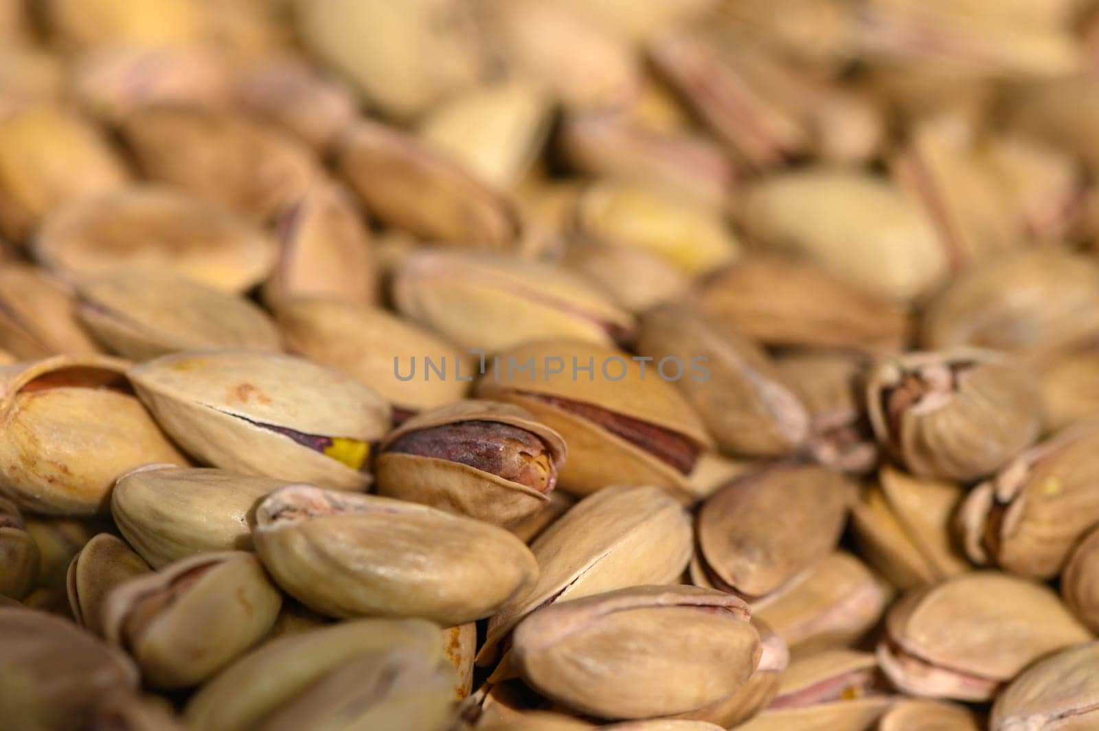 Sun-drenched pistachio nuts scattered on textured earth reveal their unique colors and shapes, showcasing nature's art in a delightful display of wholesome food.