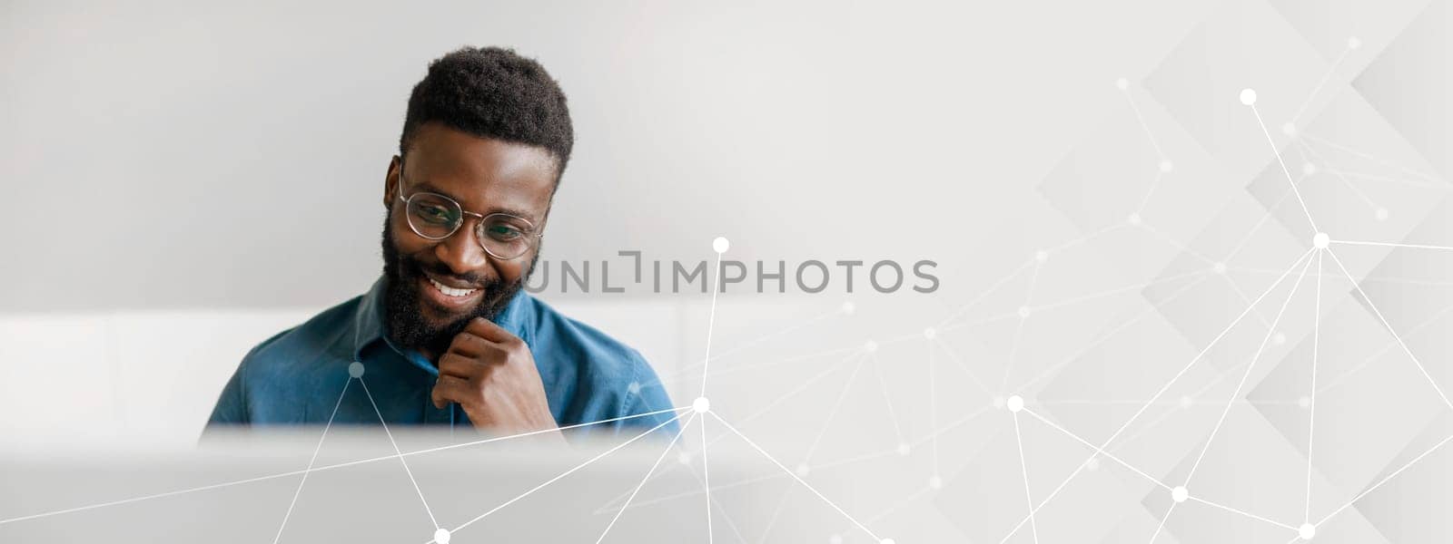 A young African American businessman sits at his desk, smiling while working on a computer. He embodies the lifestyle of a successful entrepreneur in a modern office setting, copy space