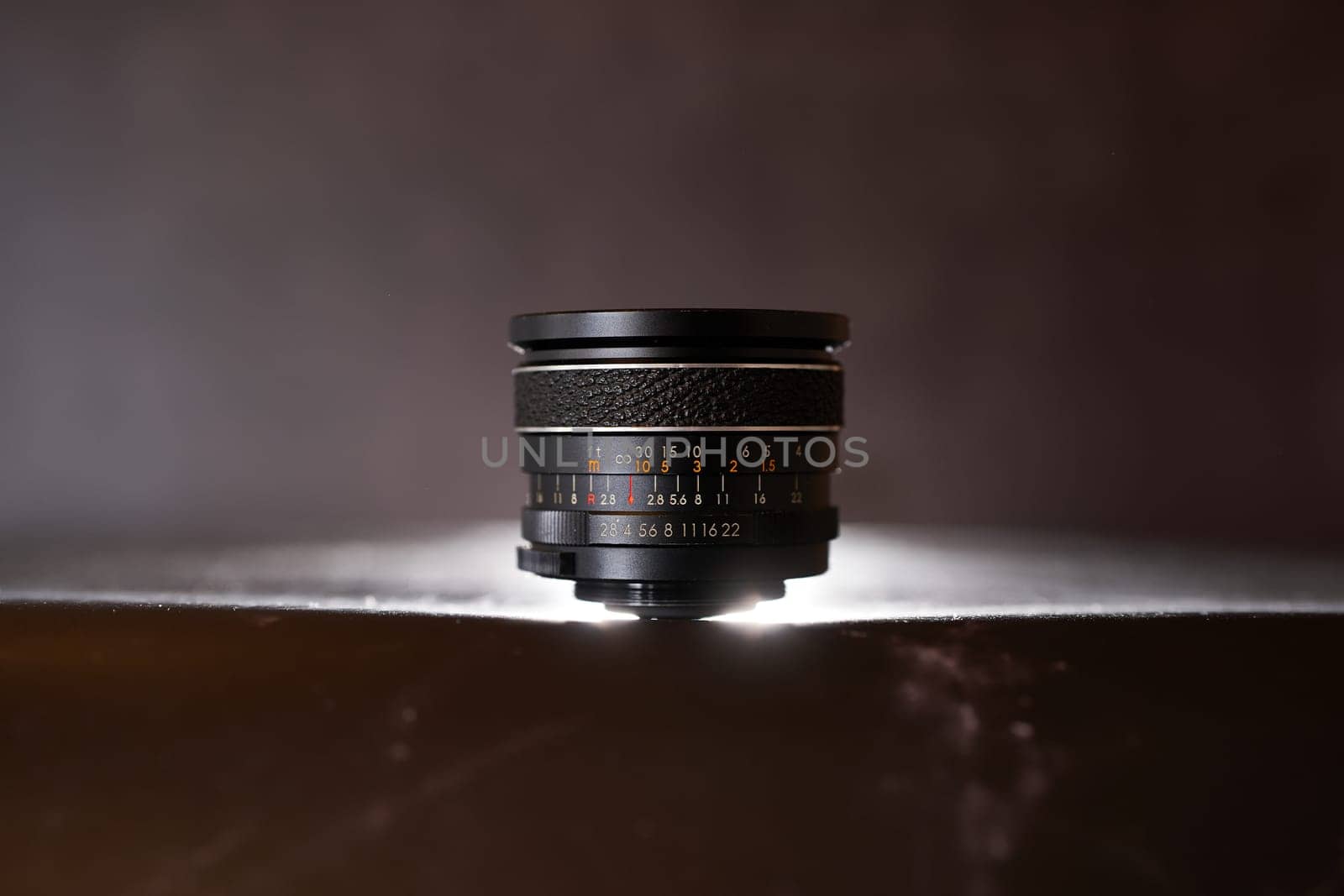 Lens for a film camera stands on a black table. High quality photo