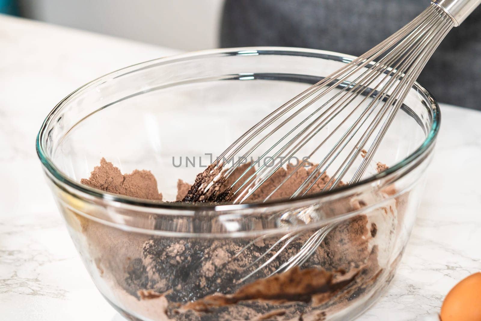 In the process of creating mouthwatering chocolate cupcakes, the first step involves meticulously mixing the ingredients in a glass mixing bowl to make the perfect batter.