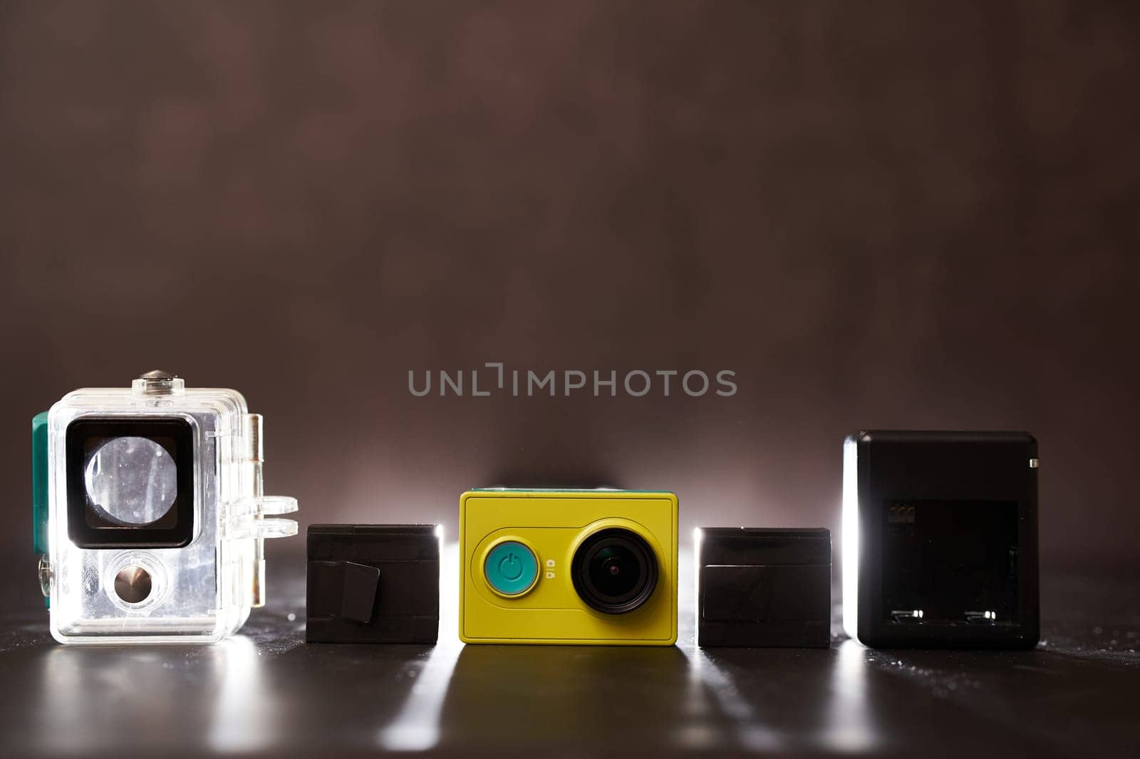 Yellow Xiaomi Y1 action camera with frame, charger and replaceable batteries stands on the table. High quality photo