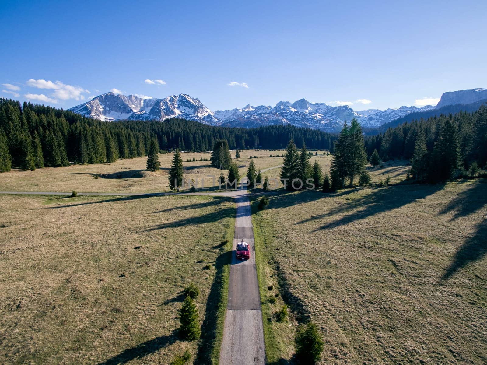 Newlyweds ride in a cabriolet on a road in a mountain valley. Aerial view. High quality photo