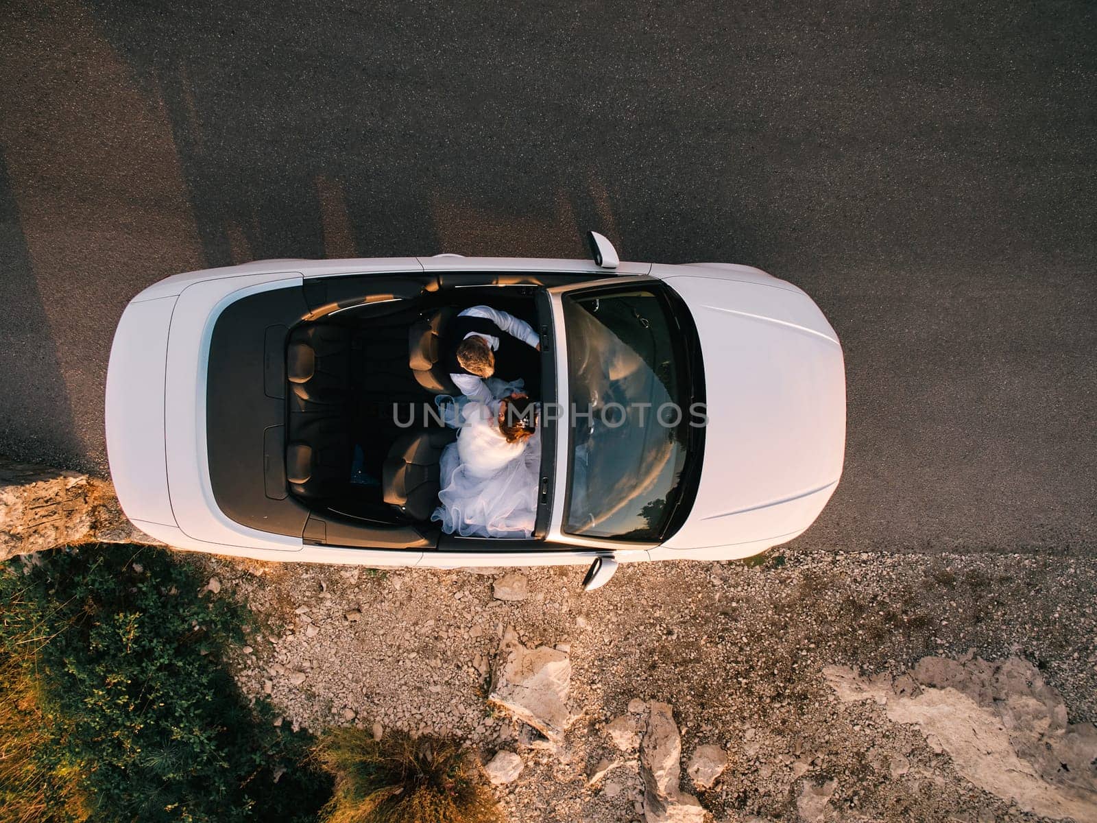 Bride and groom are driving in a white convertible on the highway. Top view. High quality photo