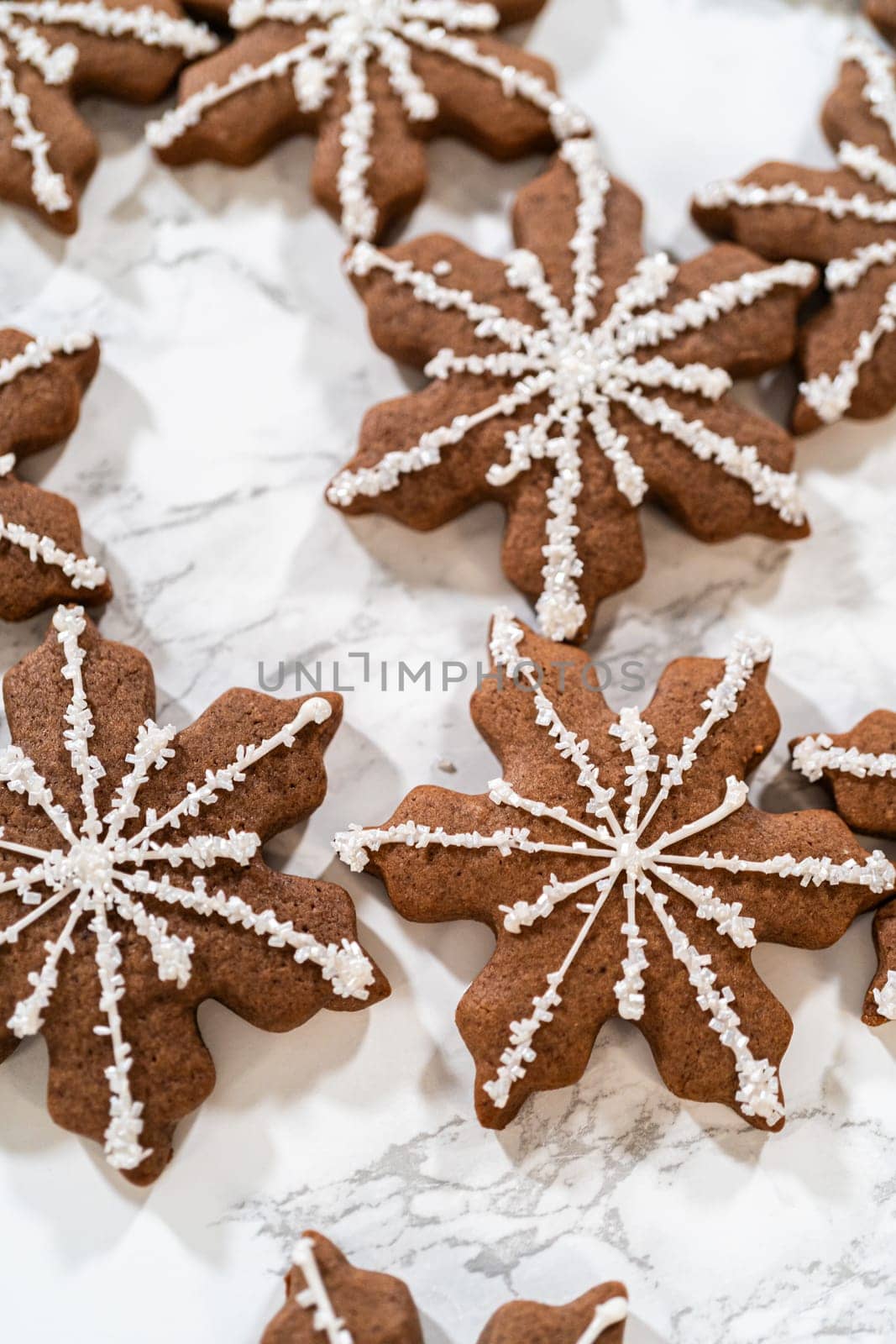 Detailed view of chocolate ginger snowflake cookies decorated with royal icing, arranged on a light background, perfect for holiday festivities.