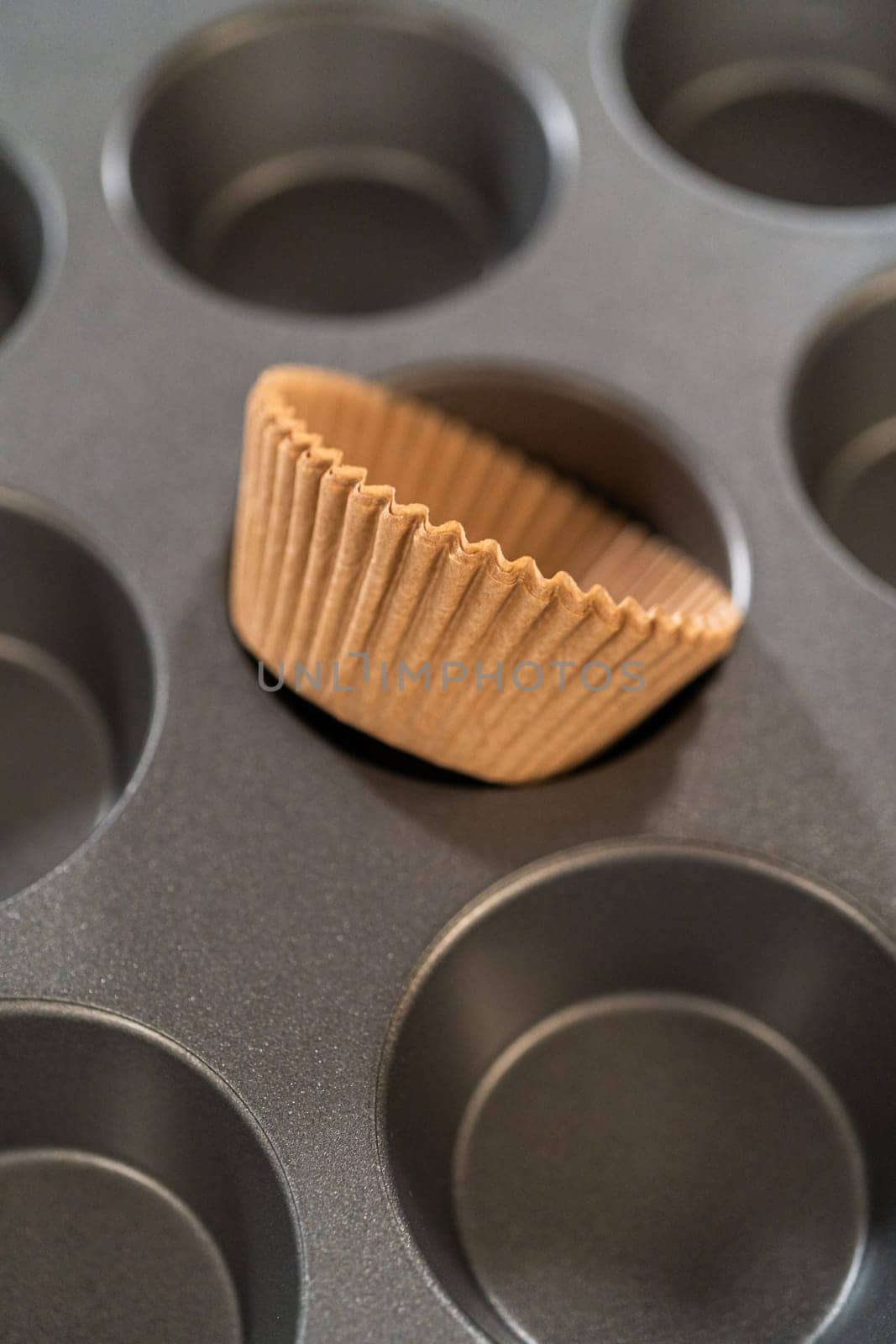 Getting ready to bake delicious chocolate cupcakes, we carefully line the cupcake pan with paper liners, ensuring a delightful treat awaits.