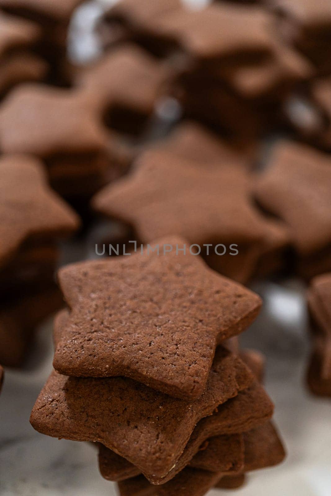 A close-up view of a neatly stacked pile of gingerbread star cookies, emphasizing their rich, spiced texture and perfect shape.