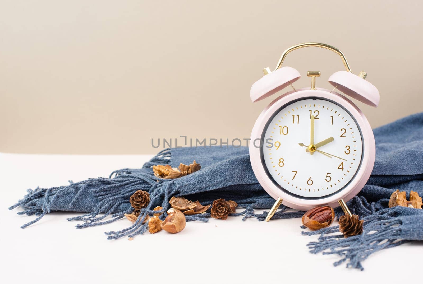 Alarm clock with a scarf and nuts, end of daylight saving time in autumn, winter time changeover