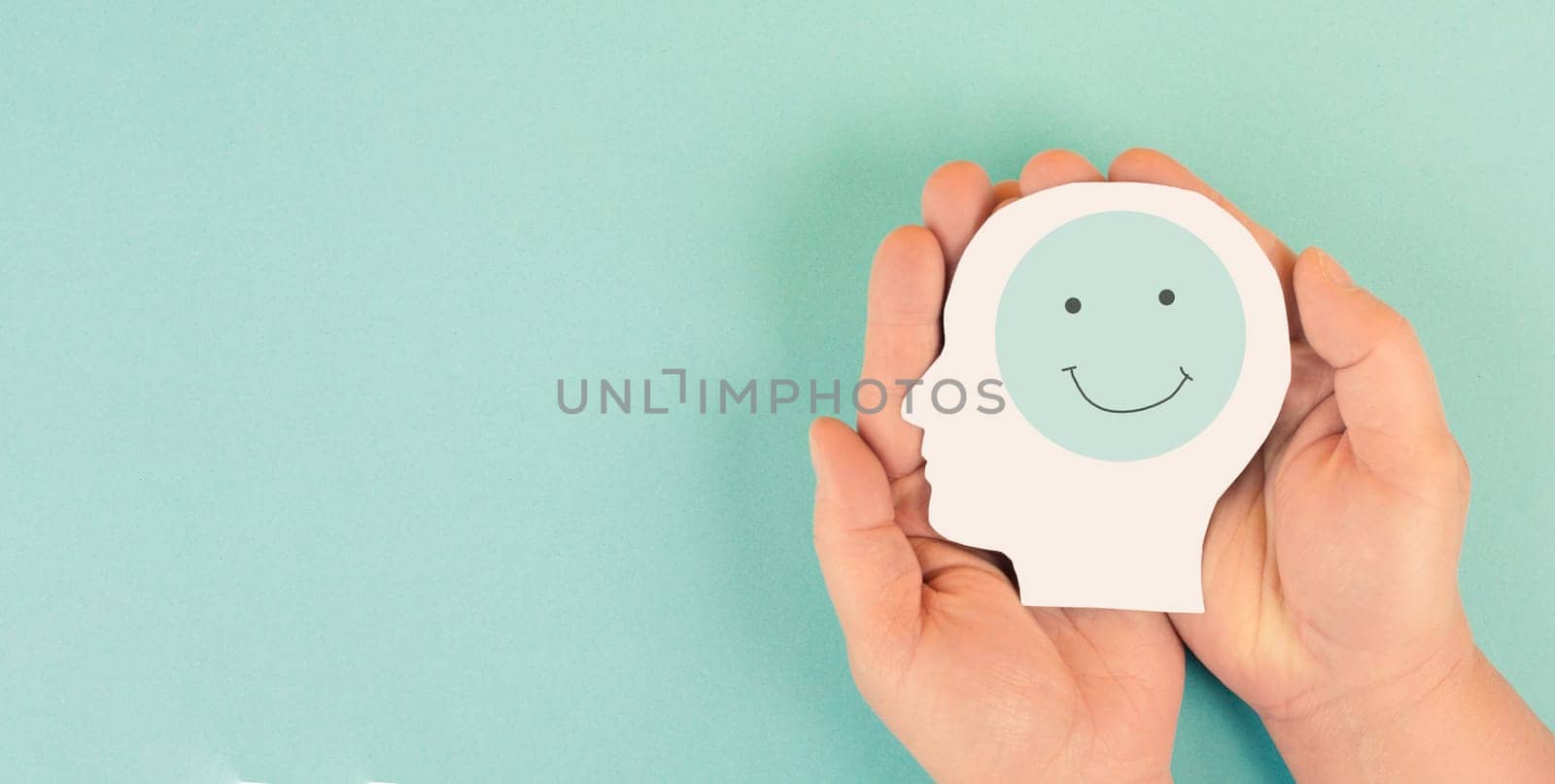 Holding a head with a happy smiling face in the hands, mental health concept, positive thinking, support and evaluation