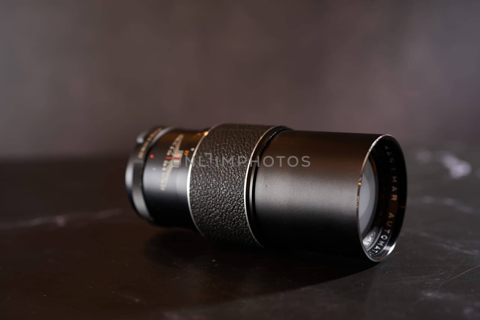 Antique Hanimar Automatic telephoto lens lies on a black table. Side view. High quality photo