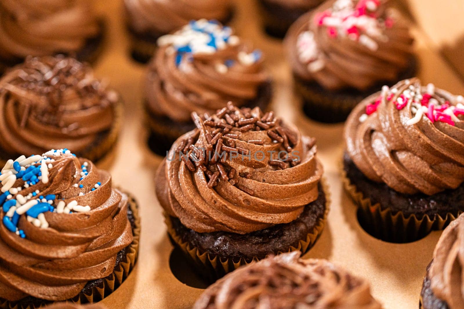 Preparing to share the delicious chocolate cupcakes, the final step involves carefully packaging them into a brown paper cupcake box.