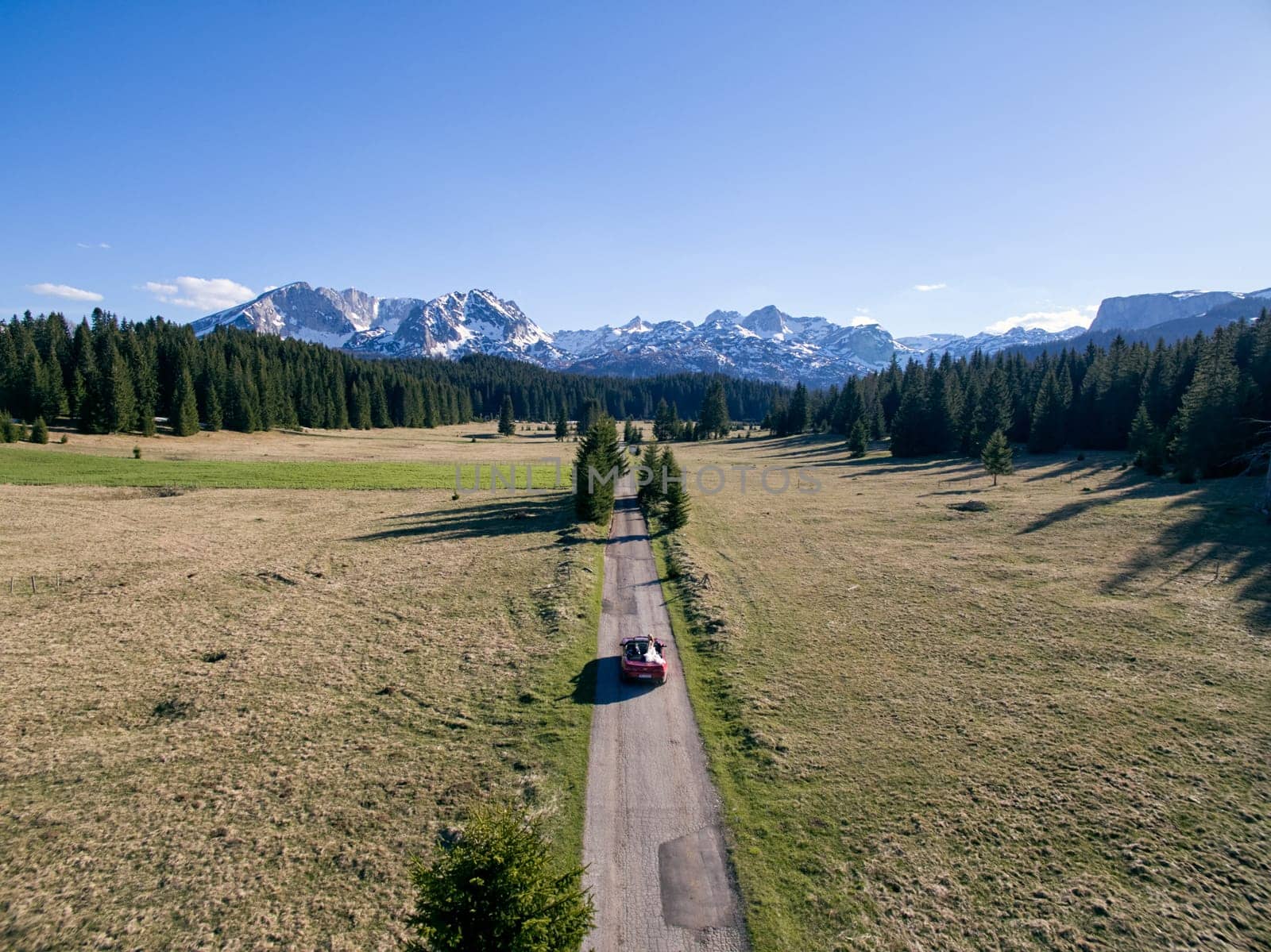 Bride and groom are driving along the highway in a mountain valley. Drone. High quality photo