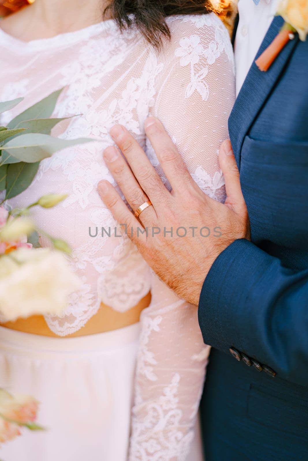 Groom hand touches bride forearm. Cropped. Faceless. High quality photo