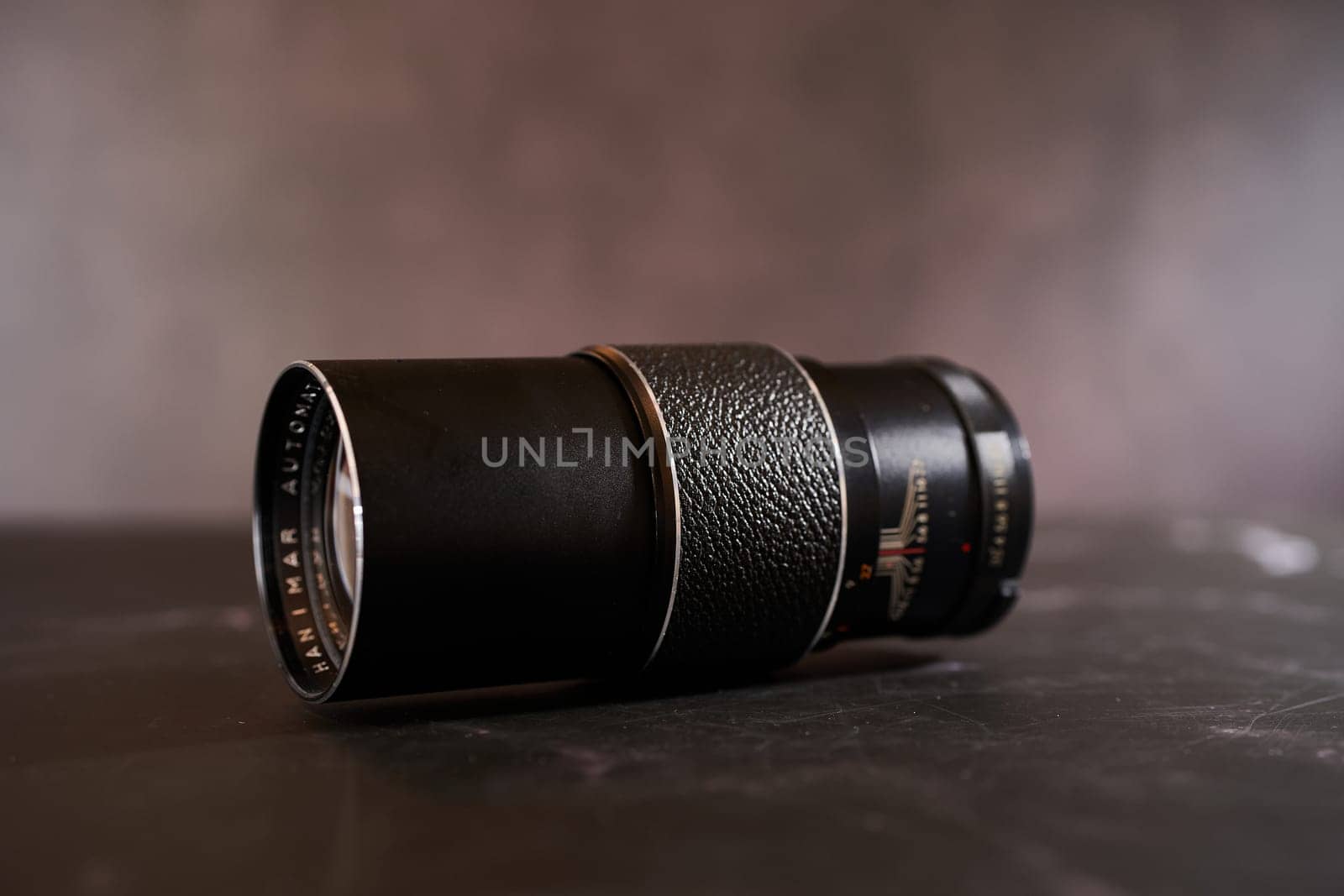 Vintage Hanimar telephoto lens lies on a black table. Side view. High quality photo