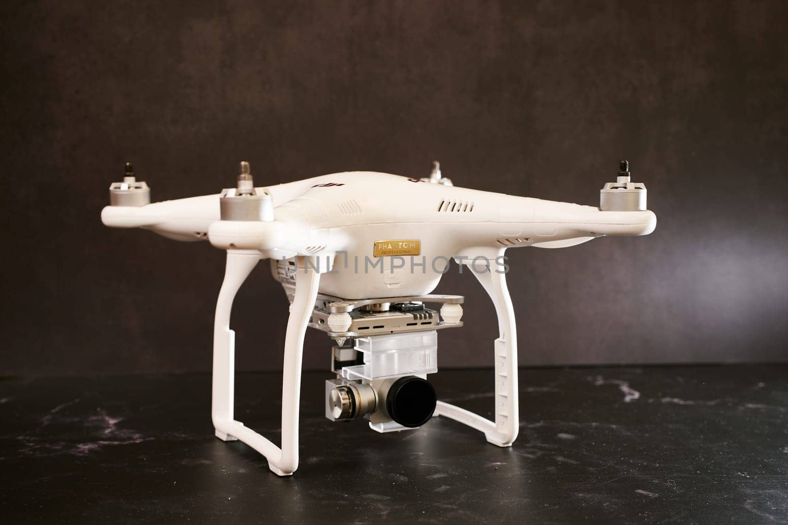 White DJI Phantom 3 UAV without propellers with a cover on a digital camera stands on a black table. High quality photo