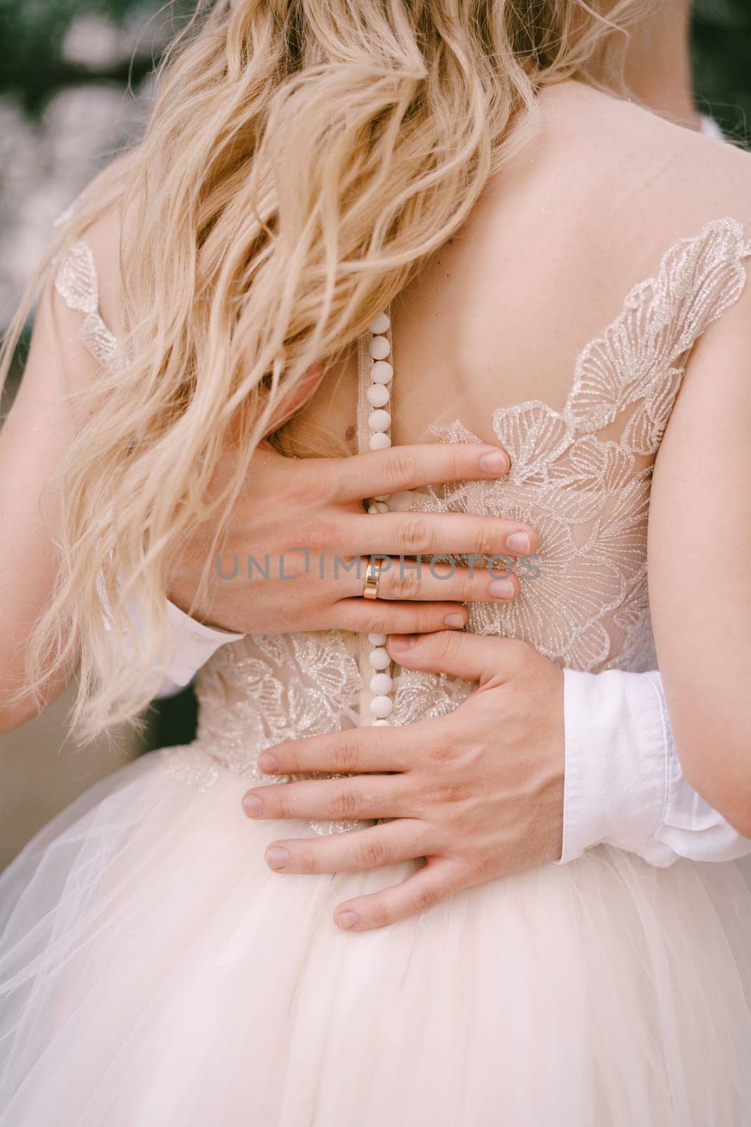 Groom hands hug the back of the bride. Back view. High quality photo