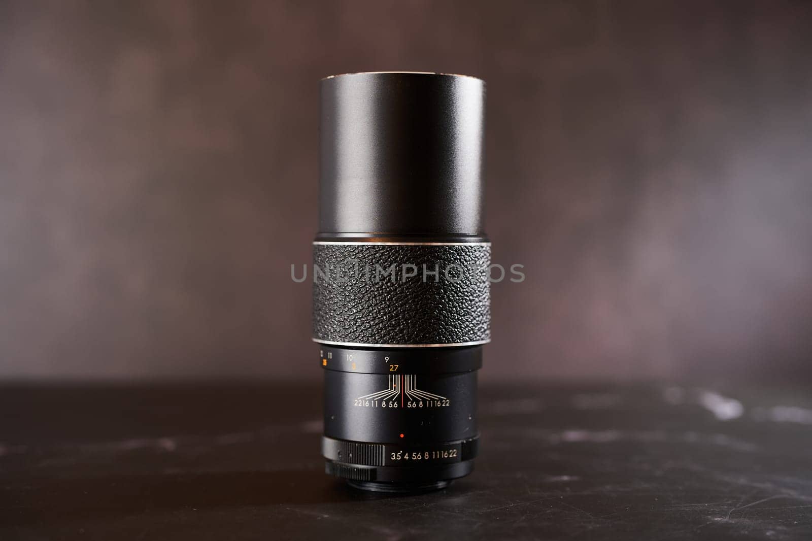 Vintage Chinon AutoZoom M42 telephoto lens stands on a black table. High quality photo