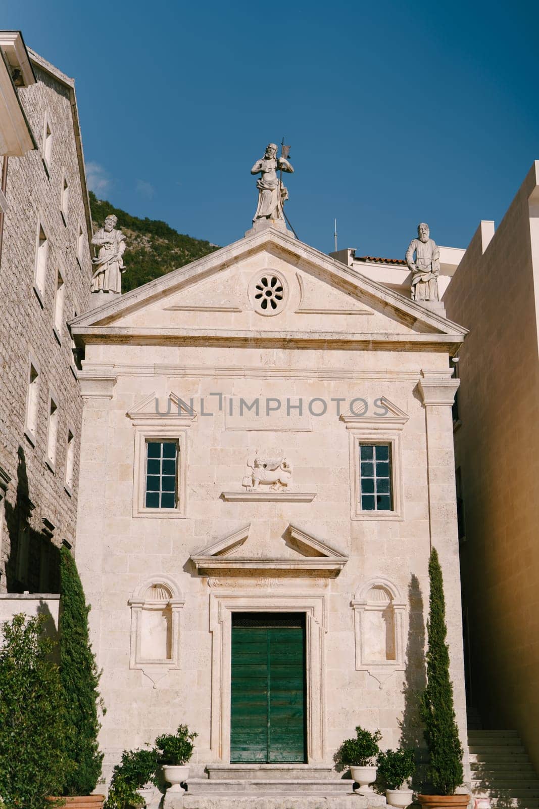 Facade of the Church of the Apostle Mark with a green wooden door. Perast, Montenegro. High quality photo