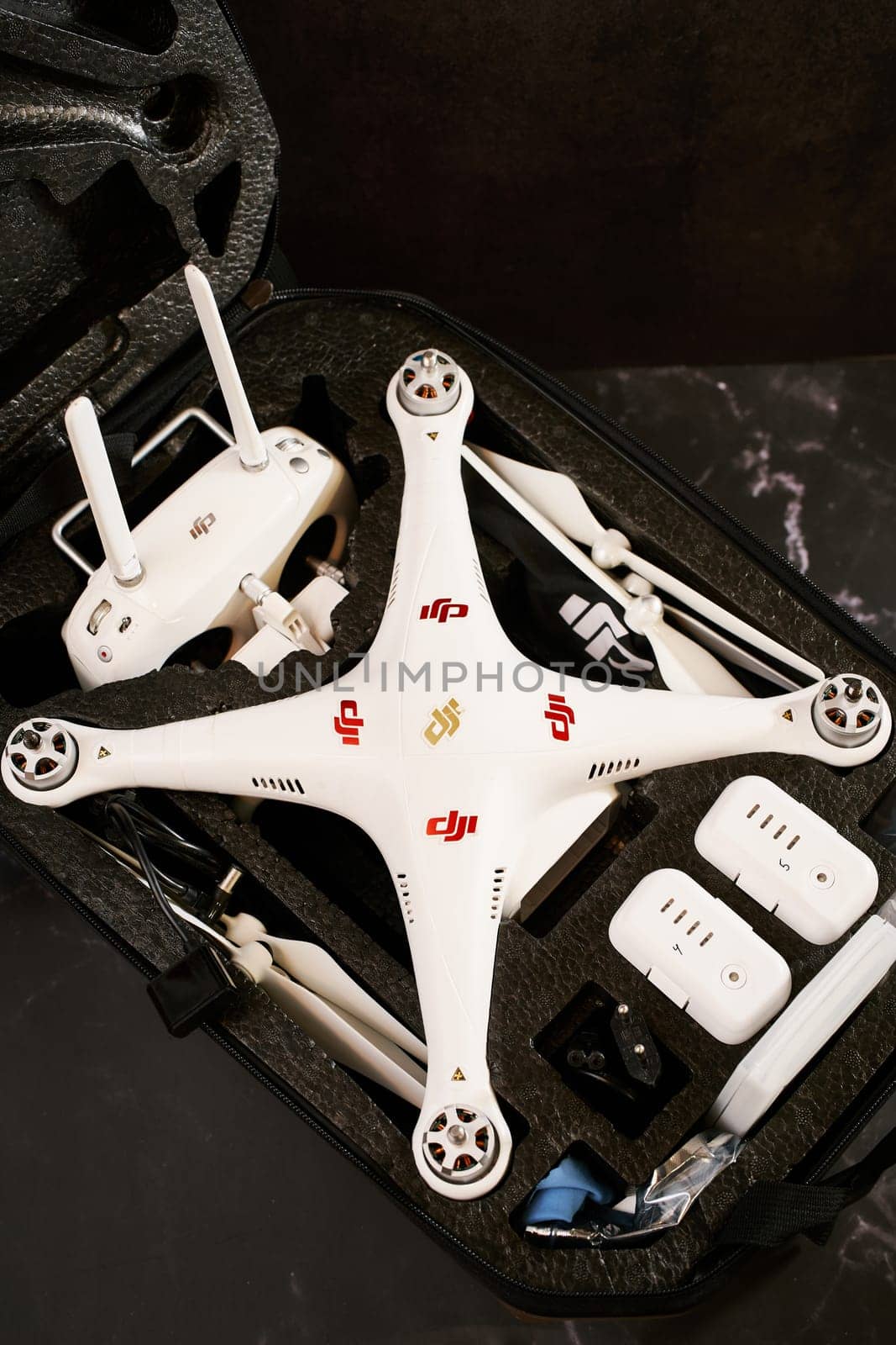 Complete set of DJI Phantom Professional drone with spare parts lies in a protective case on a black table. High quality photo