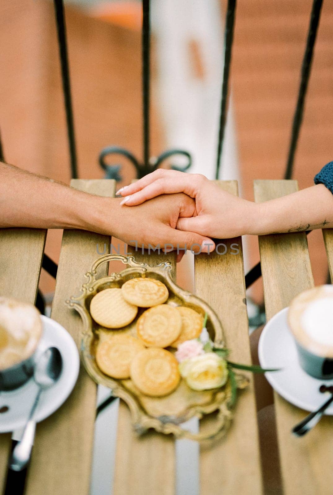 Man holds woman hand while sitting at a table with coffee on the terrace. Cropped. Faceless. High quality photo