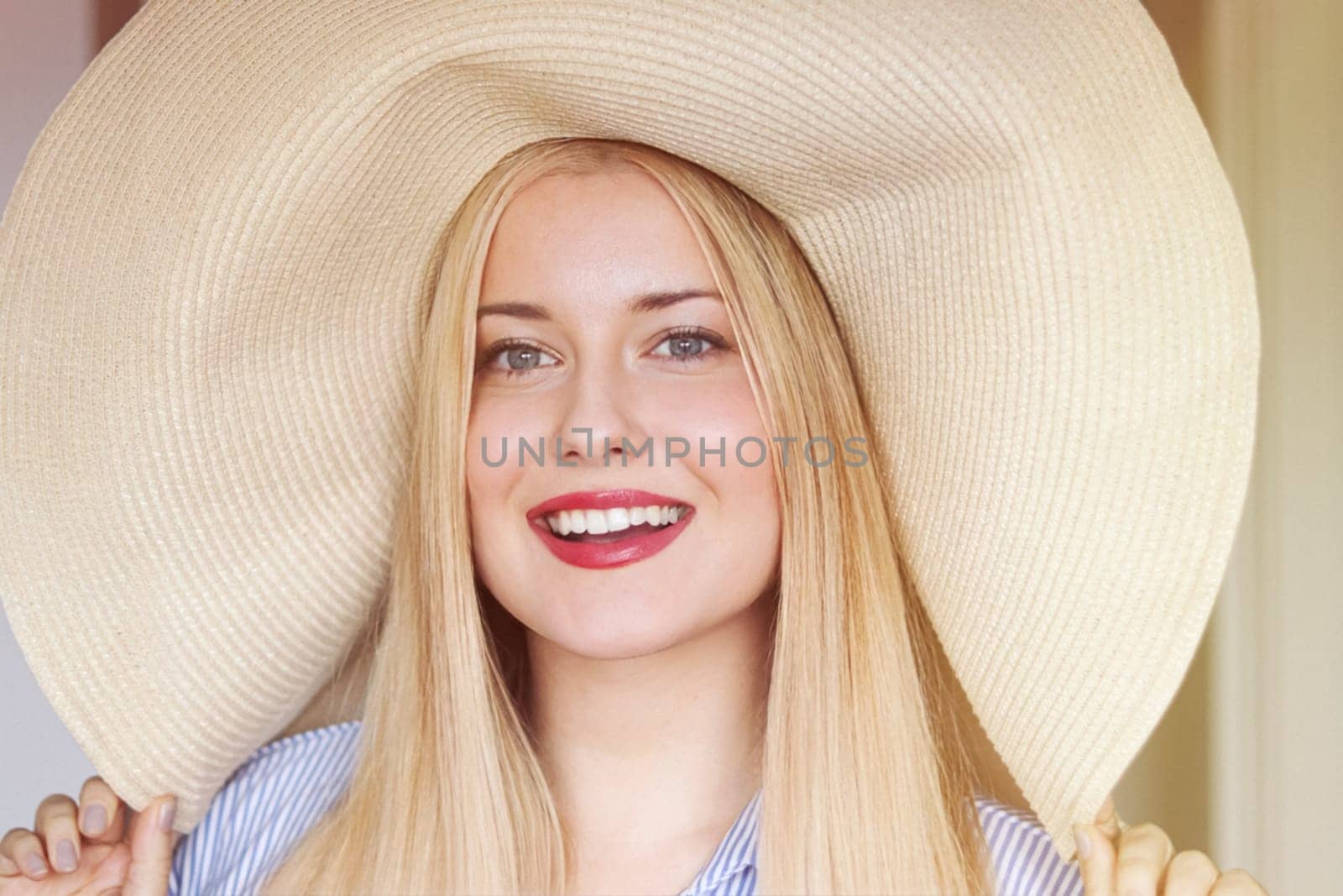 Woman, fashion and summer country charm, blonde beauty and elegance in wide brimmed beach hat. Feminine allure, timeless style and graceful glow. Smile, straw hat and blue striped blouse, natural lighting and effortless charm, fashion look idea