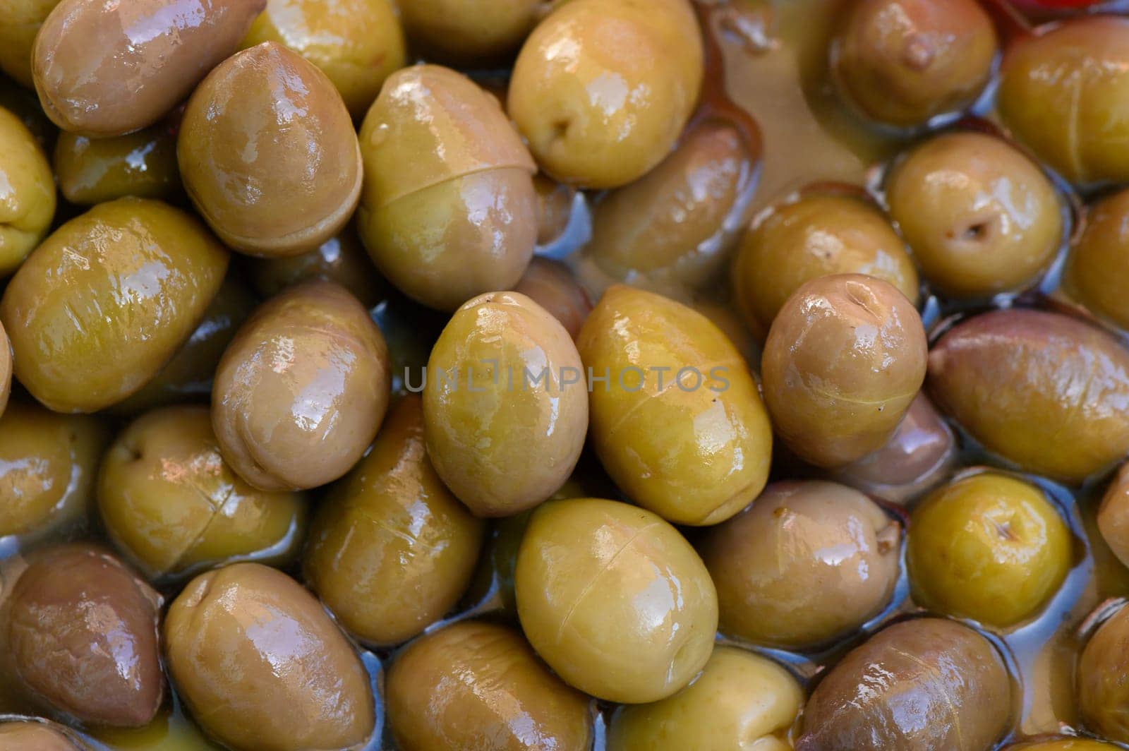 A colorful assortment of olives resting in fragrant oil fills the market stand, offering a glimpse into the rich flavors and textures that delight taste buds.