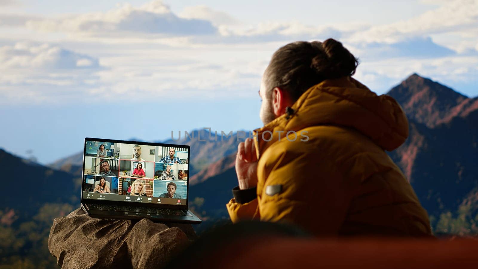Entrepreneur uses high speed internet connection on mountain top, enjoying the video call with a scenic landscape. Young hiker having an internet dependency and being workaholic. Camera B.