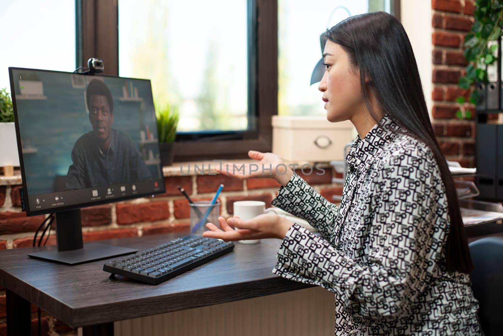 Asian woman collaborating remotely on desktop pc, discussing project plans with colleague via virtual meeting. Female advisor engaging in video call to share strategies with african american client.