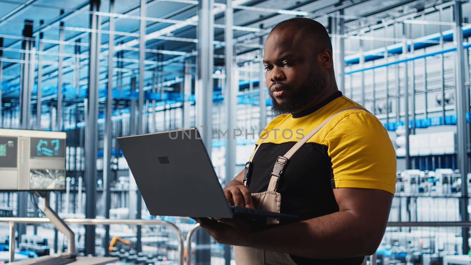 Smart factory professional implements automated workflows and control systems using laptop, computerizing manual operations. Man integrates sensors into production using notebook, camera A