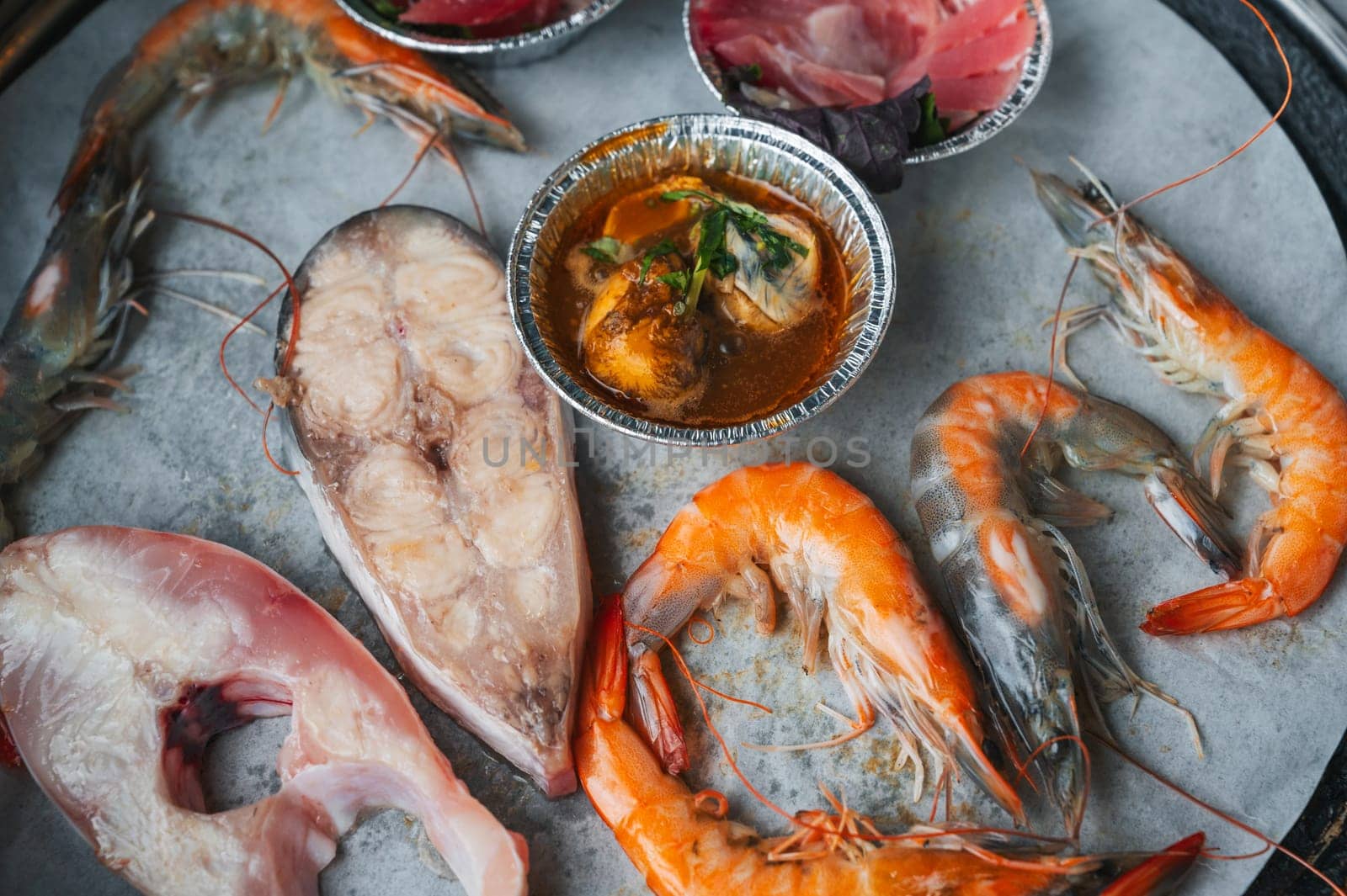 Seafood is grilled at buffet in an Asian restaurant in Asia in Vietnam. Pieces of fish and shrimp are fried on the stove