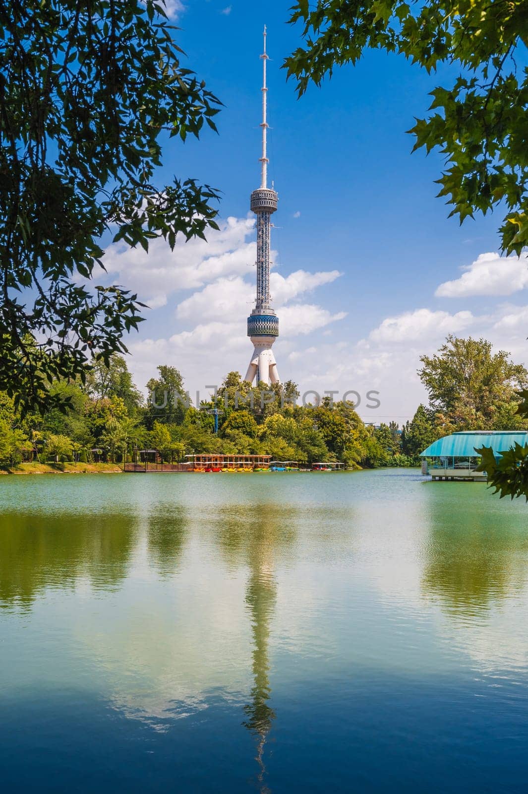 tall television tower in Tashkent in Uzbekistan against the background of a blue sky with a reflection in the pond water