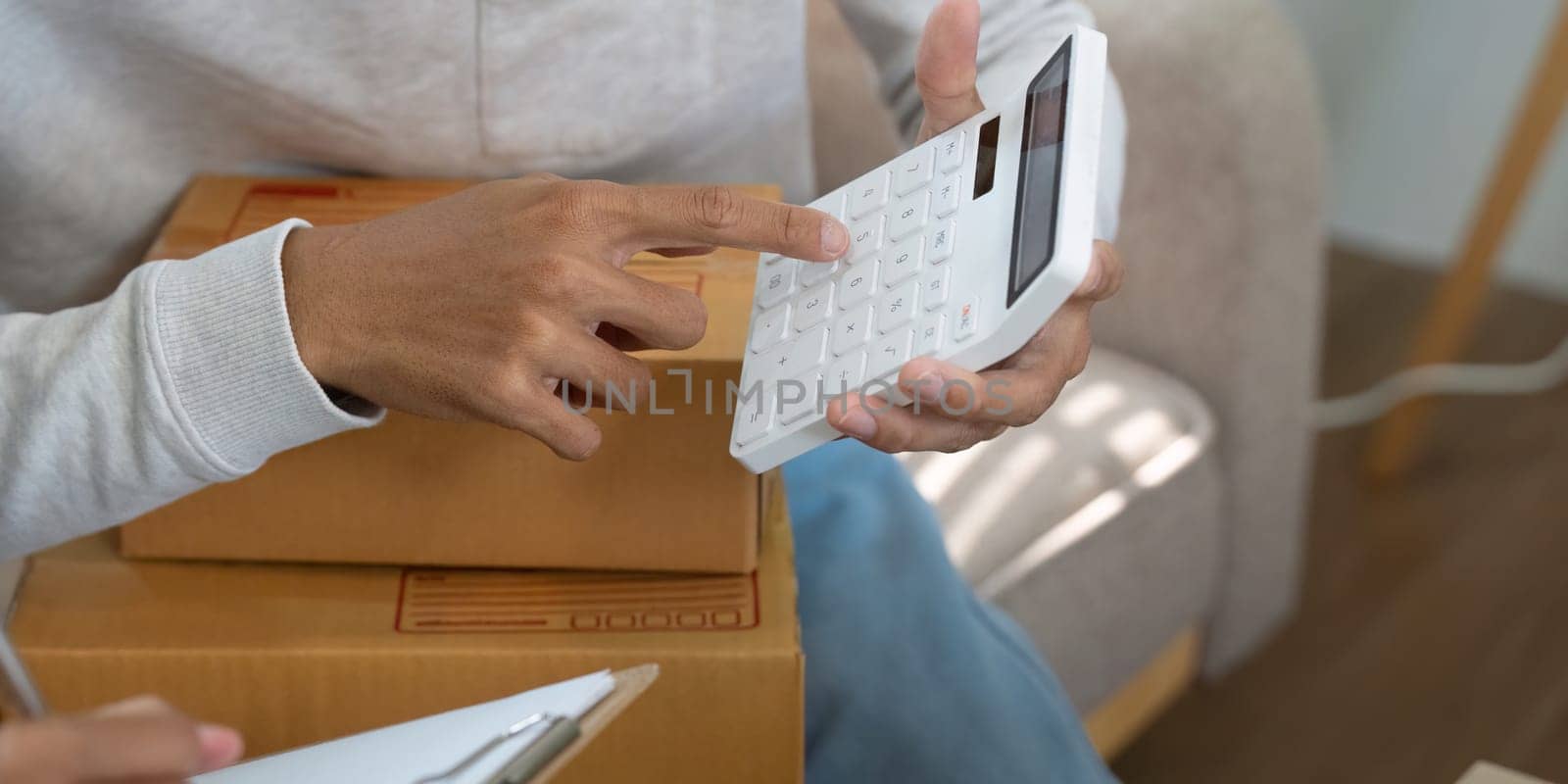 A couple focuses on financial accuracy while using a calculator to manage costs for their e-commerce business, essential for maintaining profitability.