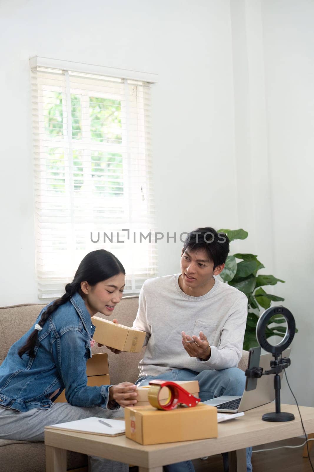 The young couple is engaged in an animated discussion about their business, sharing insights and plans as they sort through boxes in their cozy workspace.