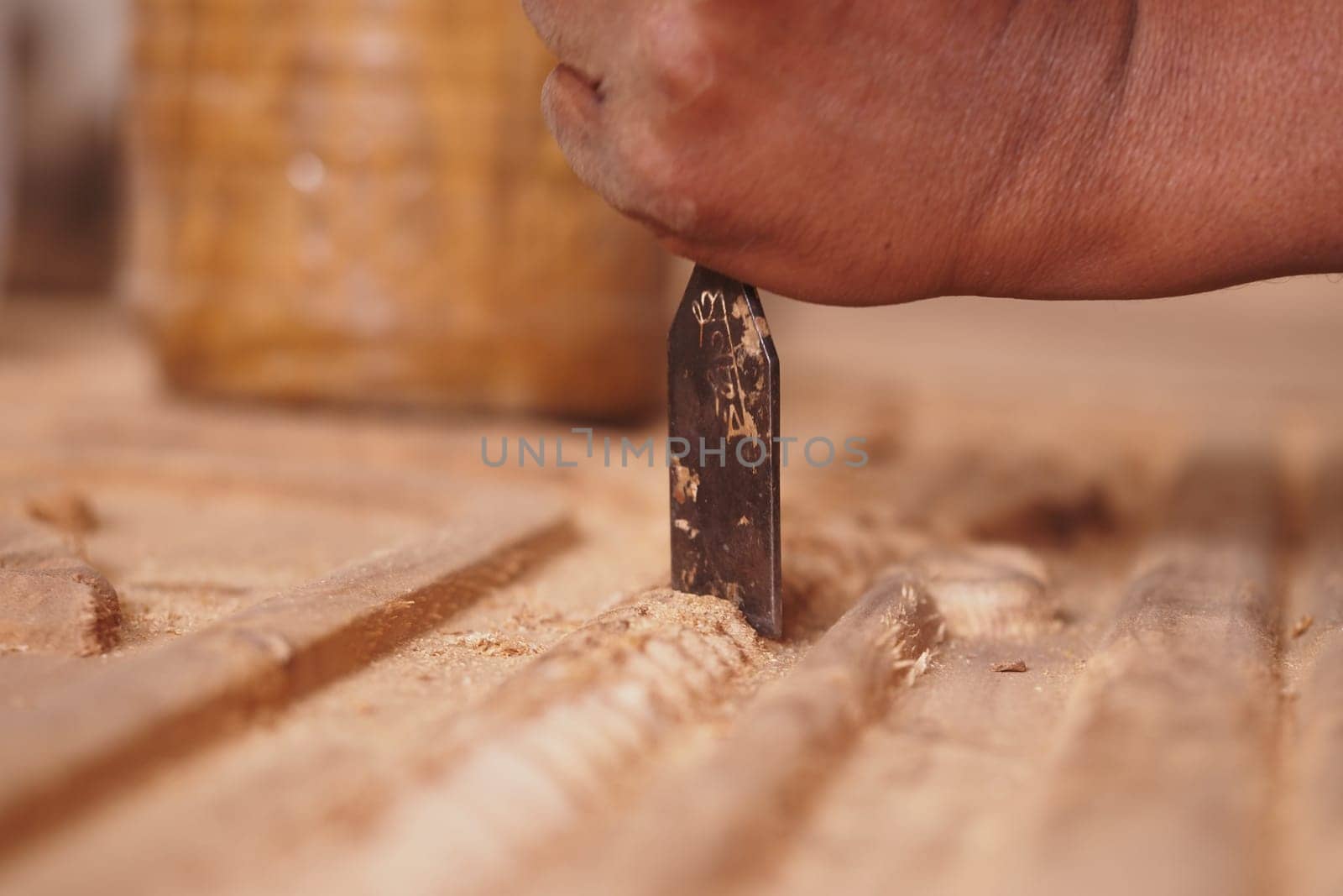 A skilled artisan carves intricate patterns into wood using a chisel.