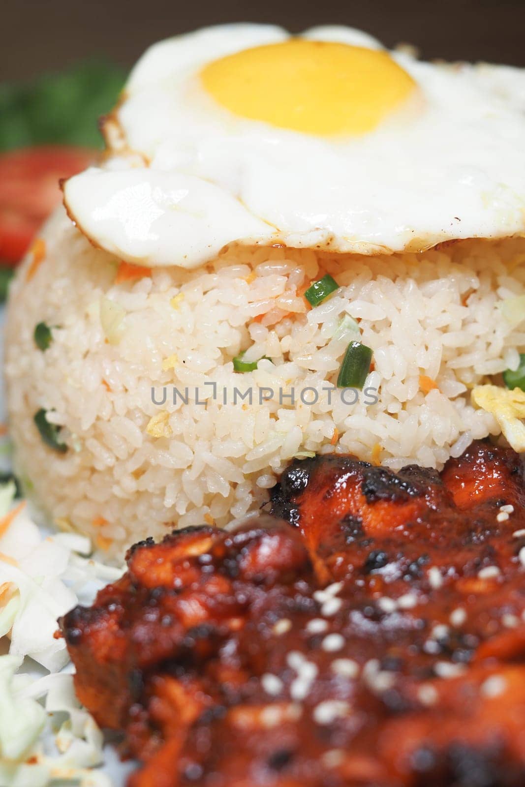 A tasty dish featuring fried rice, marinated chicken, and a fried egg.