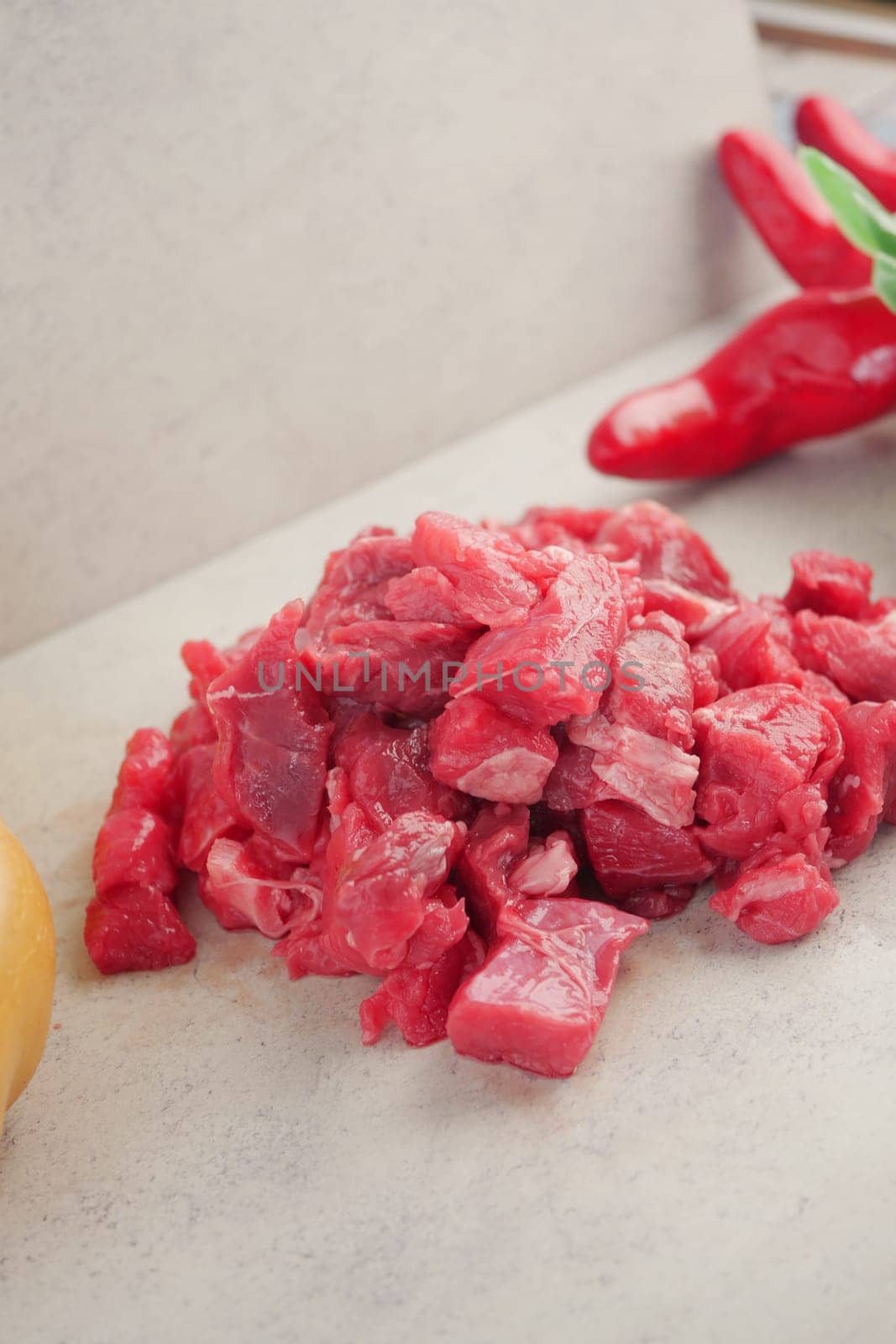 Chopped pieces of beef sit on a countertop alongside various ingredients.